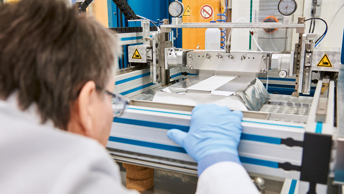 Ein Evonik-Mitarbeiter beugt sich über ein Gerät, das Separatorfolien für Lithium-Ionen-Batterien mit AEROXIDE® beschichtet.