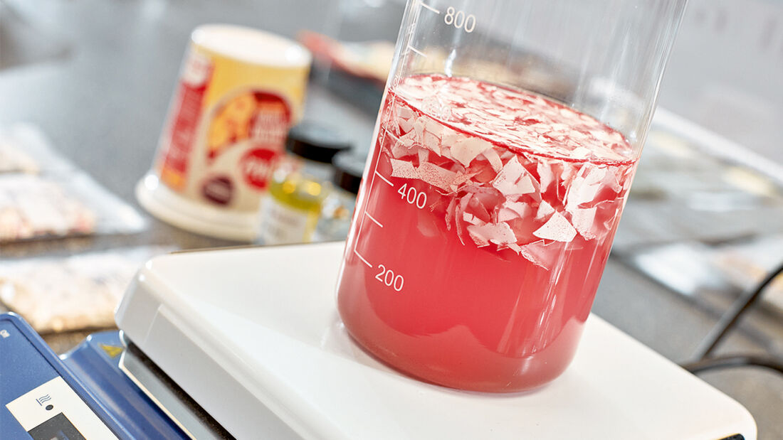 Ein Becherglas mit einer rötlichen Flüssigkeit steht auf einer Laborwaage.