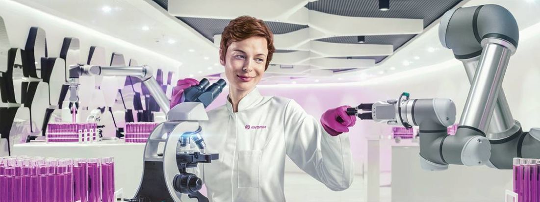 Eine Frau im Labor macht einen Faustgruß mit einem Roboter