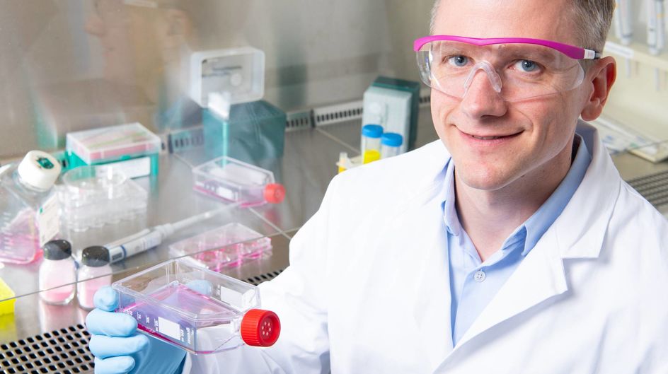 Der Leiter des Evonik-Projekthauses Tissue Engineering in Singapur, Alexander König, hält in einem Labor eine Flasche mit Nährmedium für Zellkultivierung in der Hand.