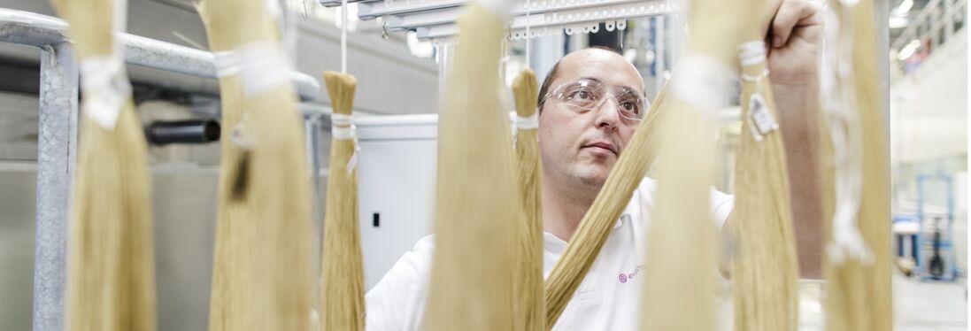 Ein Evonik-Mitarbeiter in Schörfling, Österreich, hängt gebündelte SEPURAN®-Membranfasern an ein Gestell. Die Fasern dienen der Aufbereitung von Gasen.